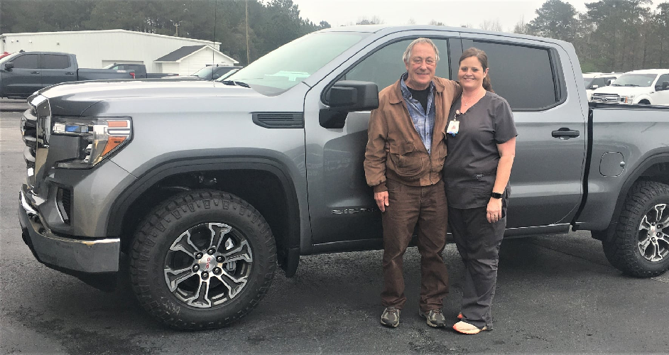 Man and woman in front of gray truck